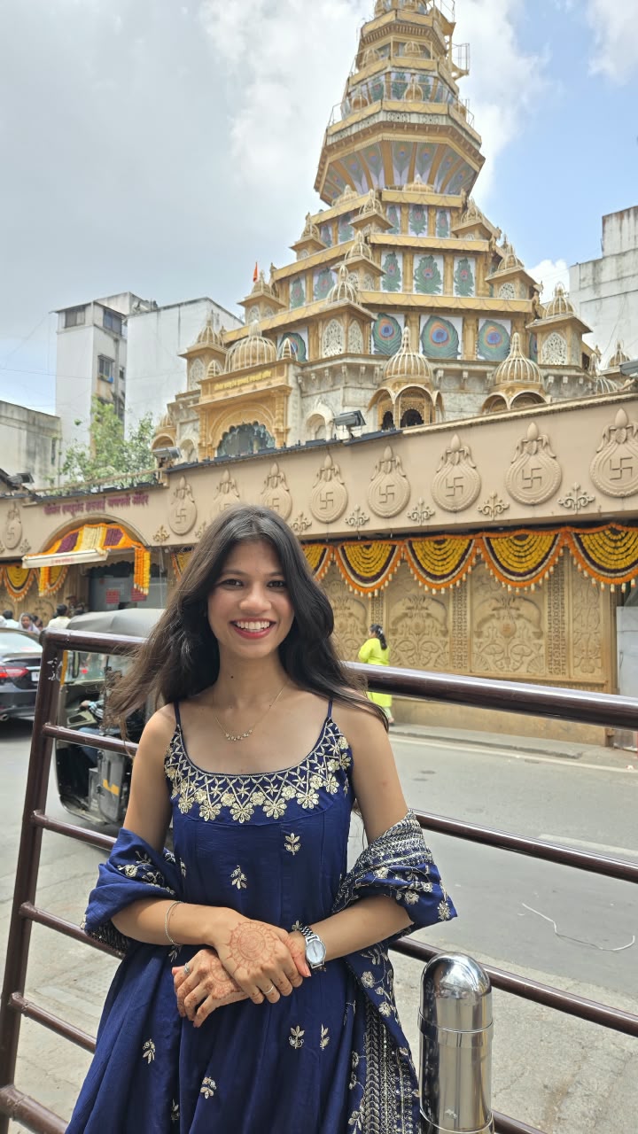 Bhakti smiling in front of a golden temple on a city street