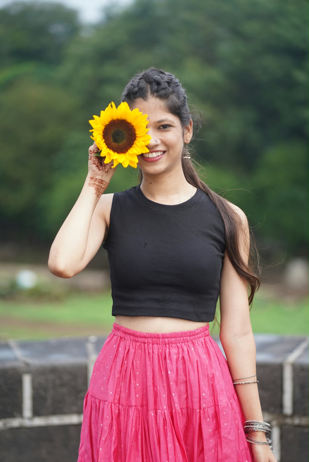 Bhakti holding a sunflower over one eye, smiling